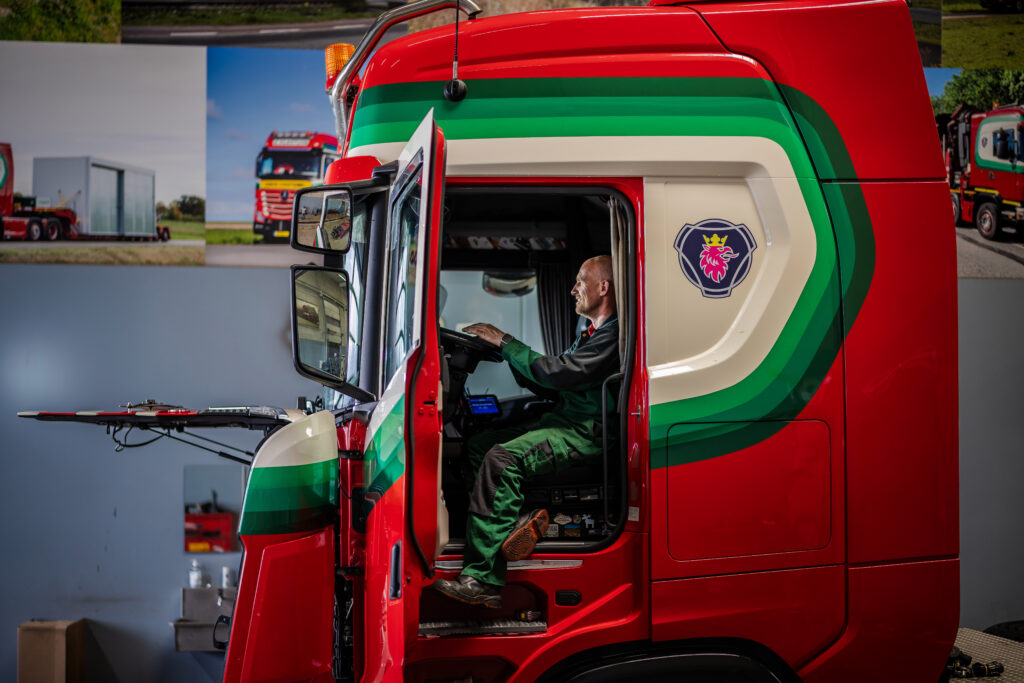 Chauffeur in de cabine van een rode Vlastuin-truck
