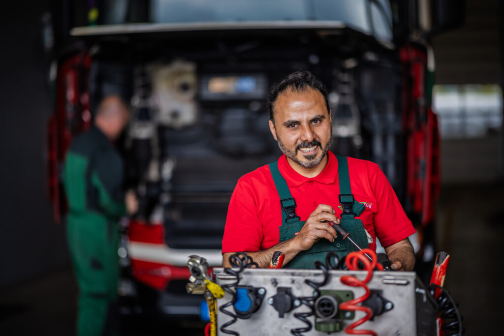 Lachende monteur met testapparatuur bij een truck